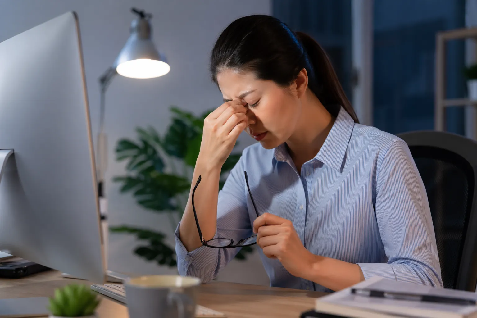 Een vrouw neemt pauze van haar computerwerk en wrijft vermoeid in haar ogen.