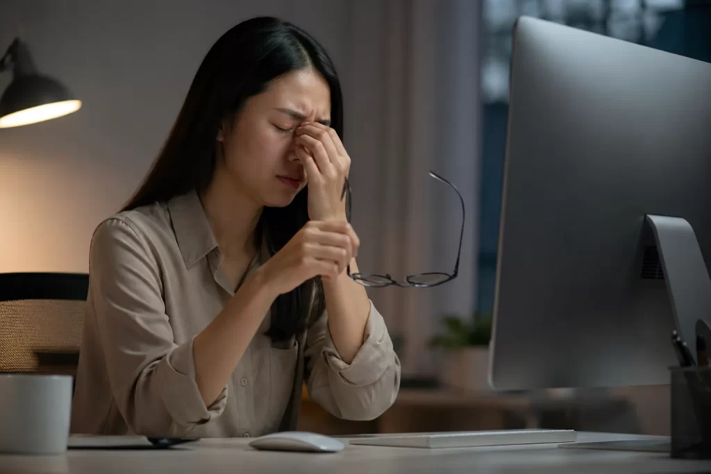 Een vermoeide vrouw wrijft in haar ogen tijdens het werken achter de computer, een herkenbaar beeld van digitale oogbelasting.